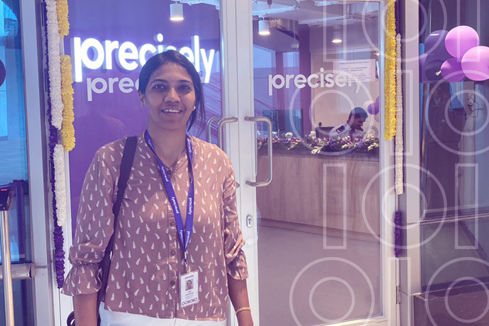 Jothi poses and smiles in front of the Precisely offices.