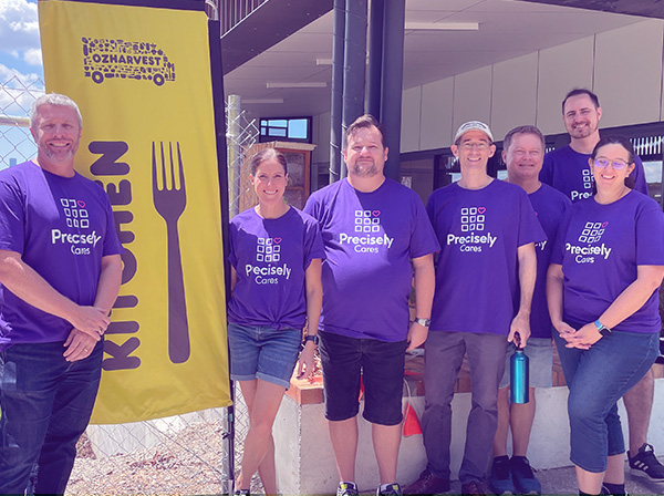 A group of Precisely employees pose during a community event.
