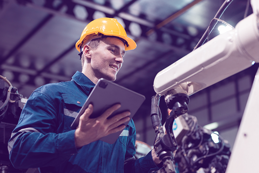 Man using a tablet to monitor automated manufacturing equipment